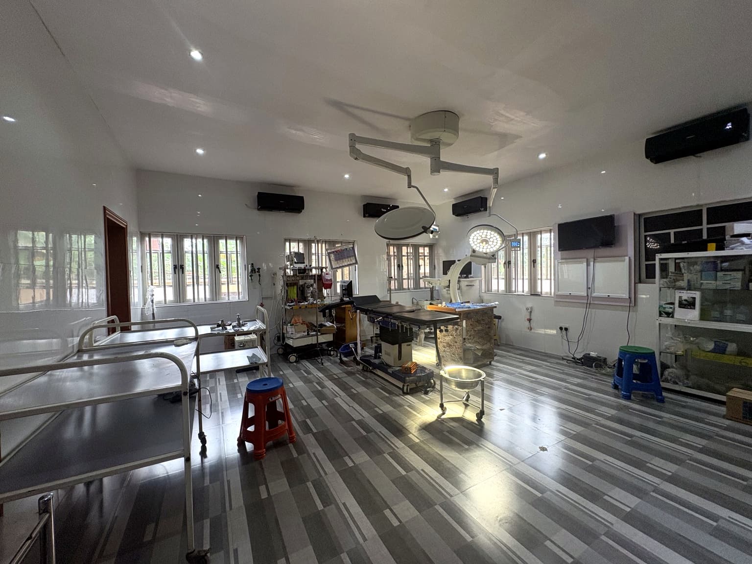 Wide view of an operating theatre at Banby Specialist Hospital in Ibadan, with instrument trolleys, the operating table and supply shelving