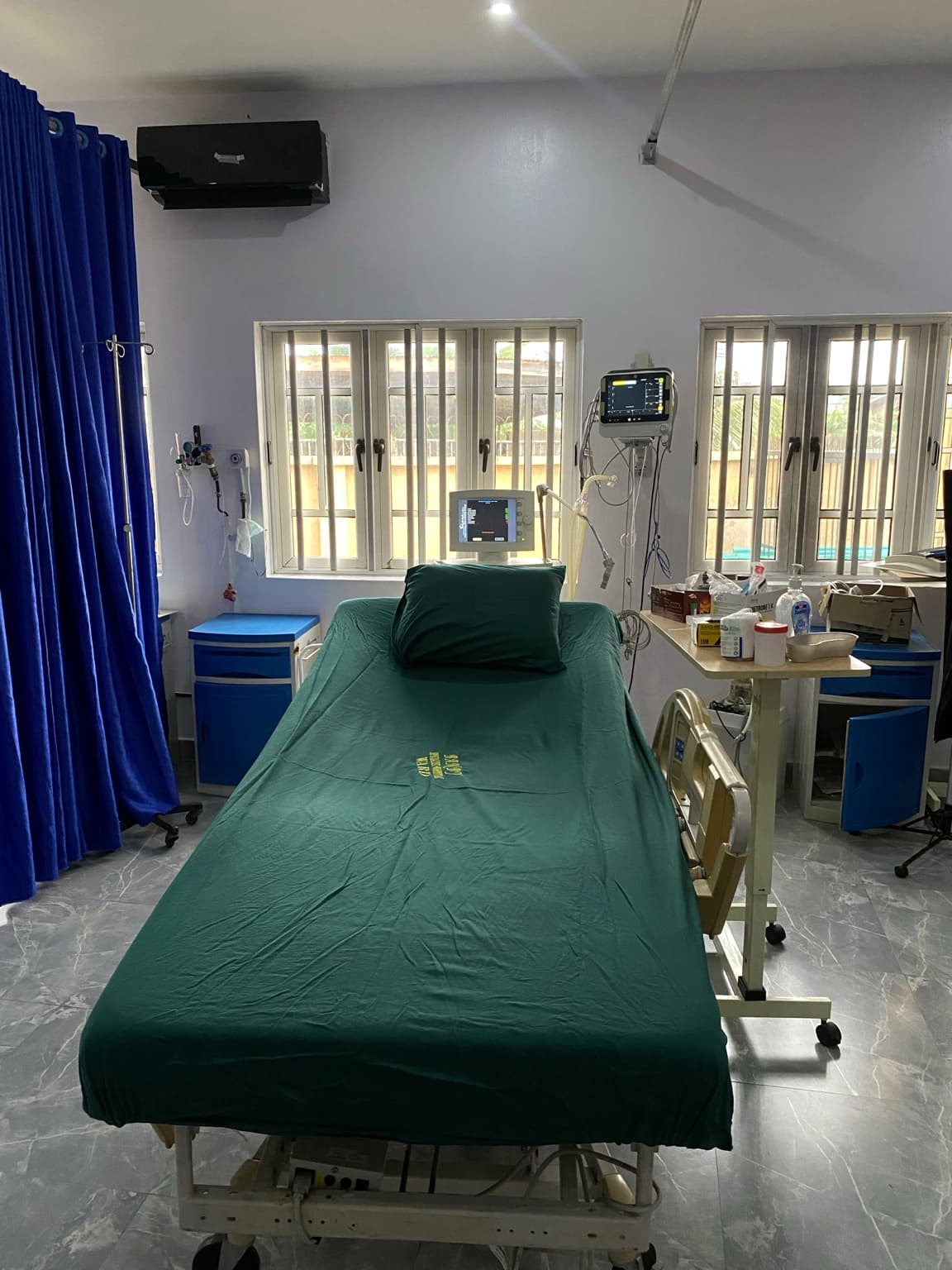Private patient room at Banby Specialist Hospital in Ibadan, with a bed made up in green linen, a bedside monitor and piped oxygen