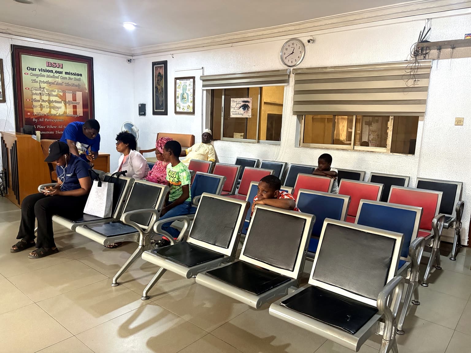 Patients seated in the waiting area at Banby Specialist Hospital in Ibadan, beside the HMO desk windows