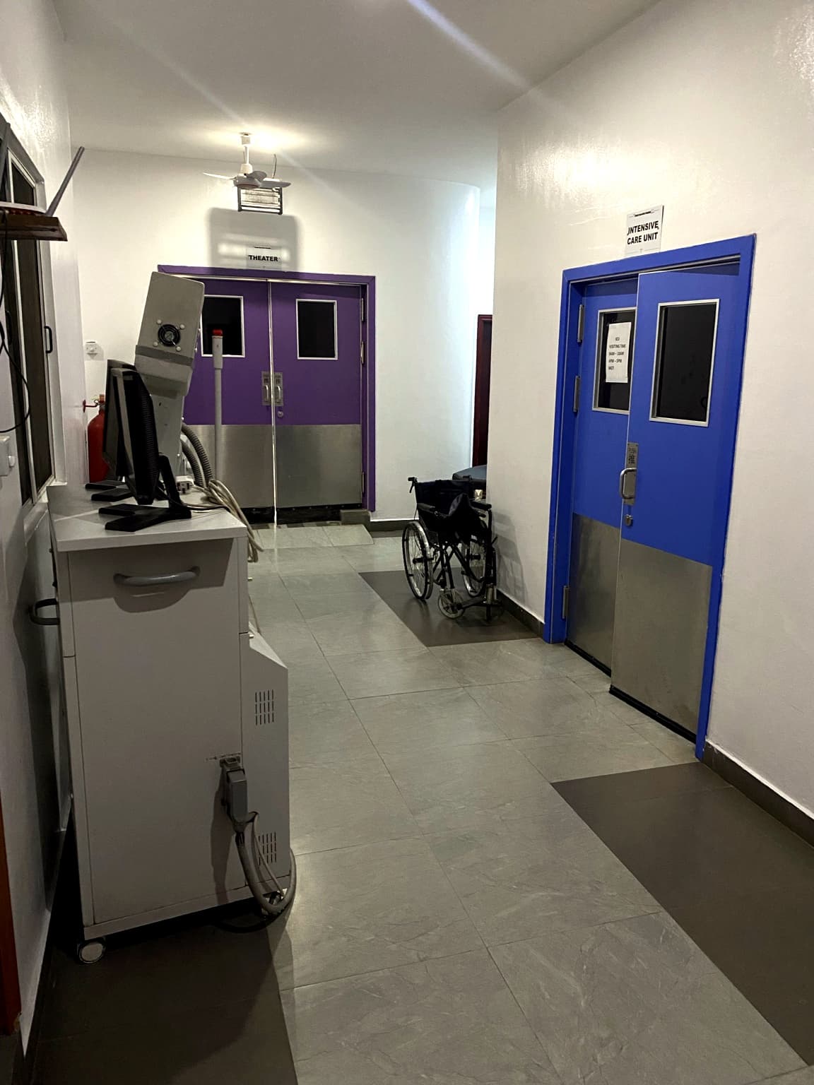 Corridor at Banby Specialist Hospital in Ibadan leading to the theatre and Intensive Care Unit doors, with a wheelchair parked alongside