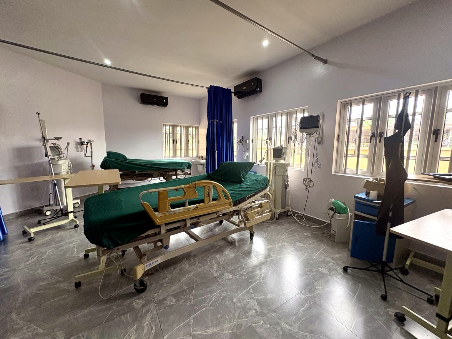 Two-bed ward at Banby Specialist Hospital in Ibadan, with beds made up in green linen and monitoring equipment at the bedside